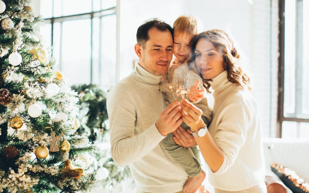 A family of three celebrating the holiday season, standing near a decorated Christmas tree and holding sparklers. Keywords: family holiday celebration, festive season, joyful moments.